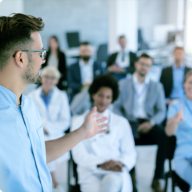 male professional speaking to a classroom filled with business and clincal professionals
