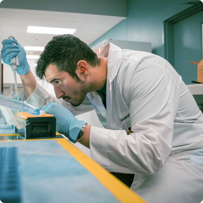 male researcher holding lab equipment and closely examining materials in a laboratory