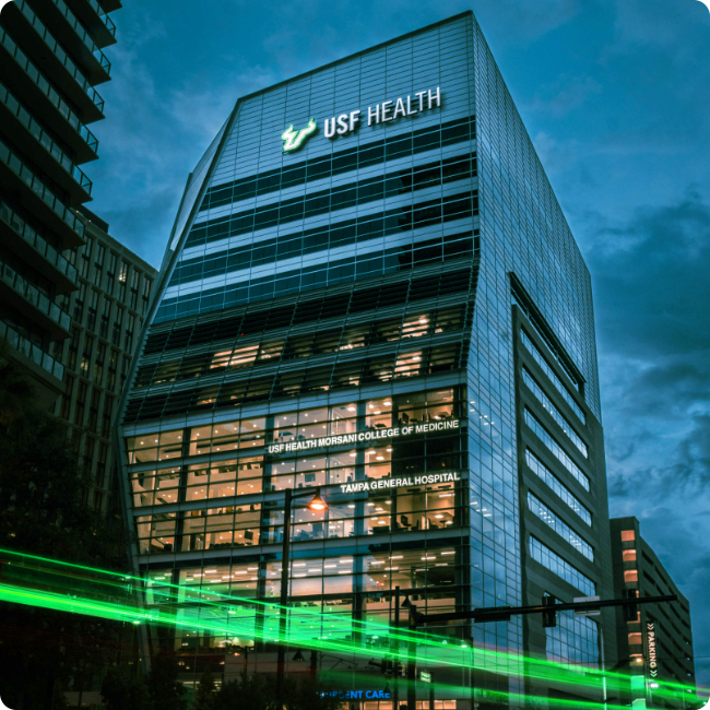 usf health morsani college of medicine building in the tampa medical and research district at night with green motion line in foreground