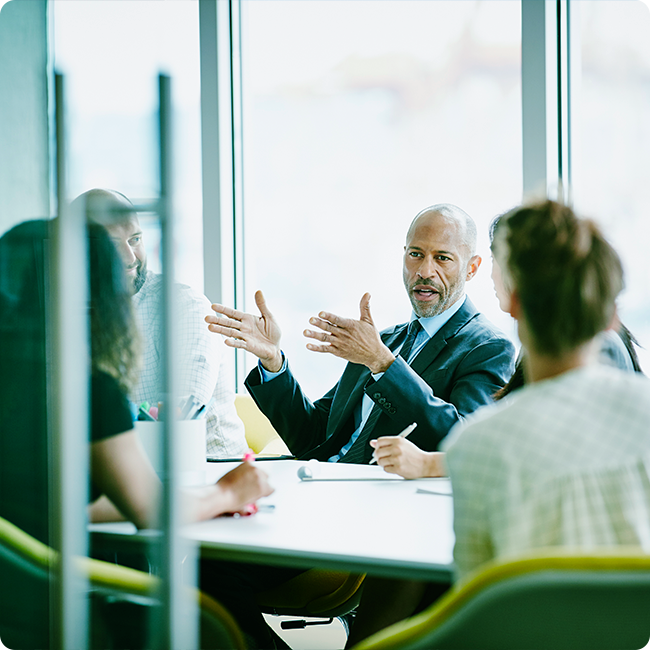 male business professional speaking to colleagues in a conference room about innovation