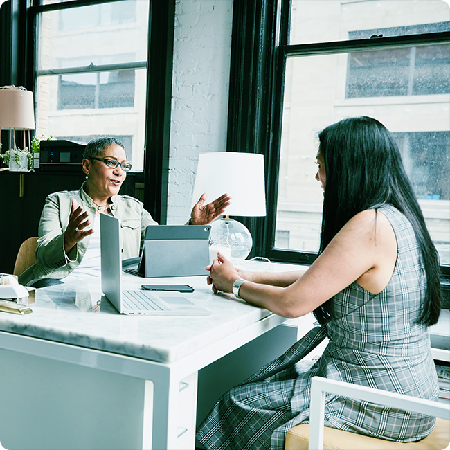 two female business professionals meet in an office to network and discuss innovation